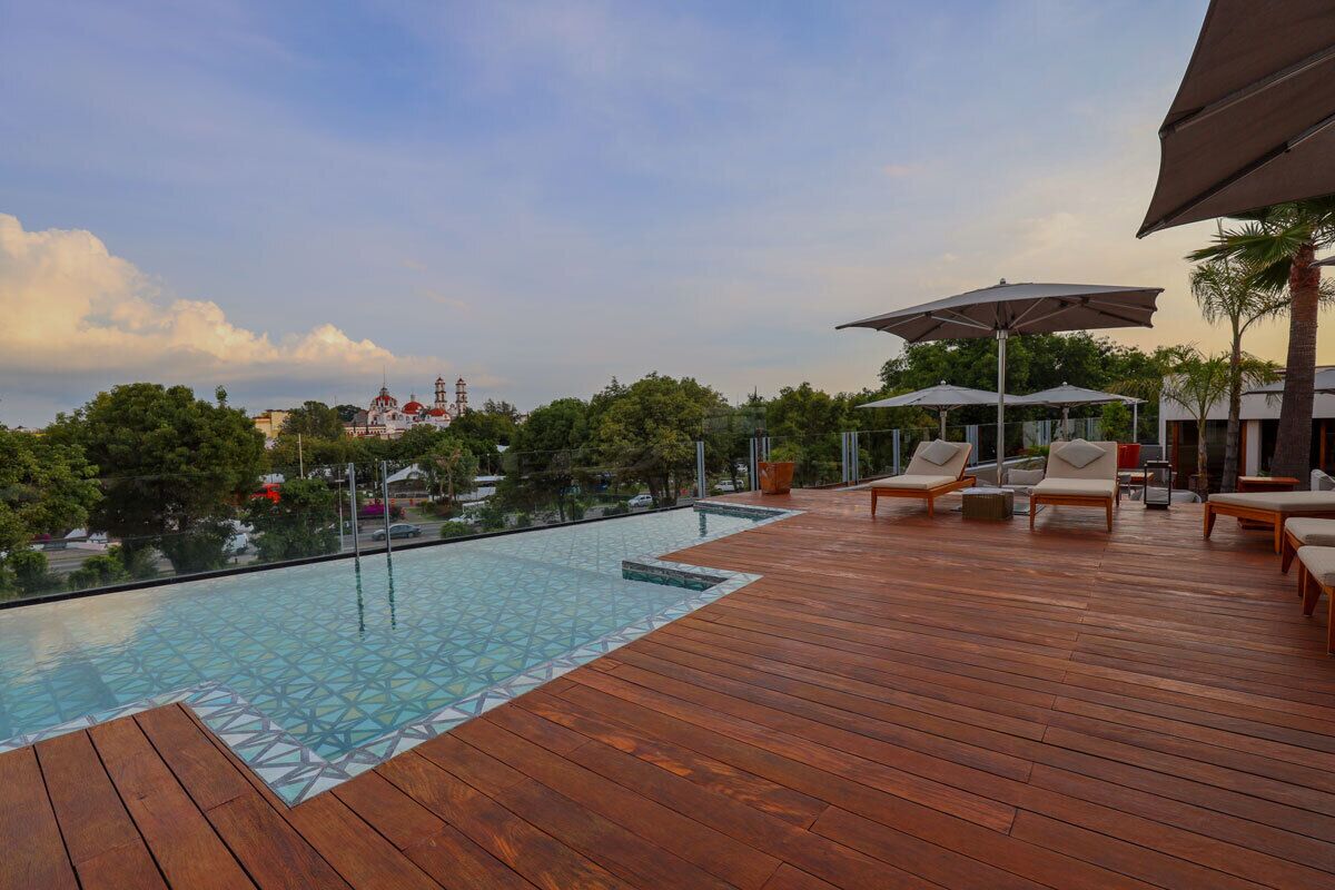 A wooden deck with a pool, lounge chairs, and umbrellas.