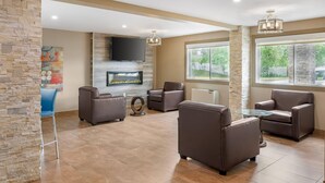 A spacious living area with a stone accent wall, a flat-screen TV mounted above a fireplace, and comfortable seating. - Quality Inn & Suites Bathurst (Bathurst)