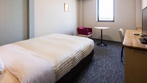 Une chambre d’hôtel avec un lit, un bureau, une chaise, une petite table et une fenêtre.