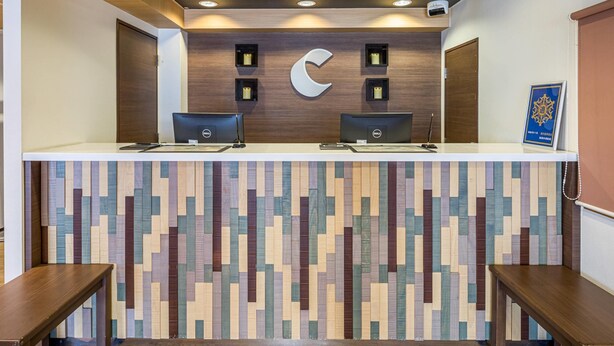 Un comptoir d’accueil doté de deux postes informatiques, d’un mur recouvert de panneaux en bois et d’un sol à motifs.