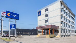 Un hôtel Comfort Inn avec une façade moderne, un panneau indiquant le stationnement et un panneau NISS en arrière-plan.