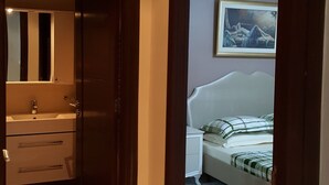 Een slaapkamer met een bed, nachtkastje en een schilderij aan de muur.