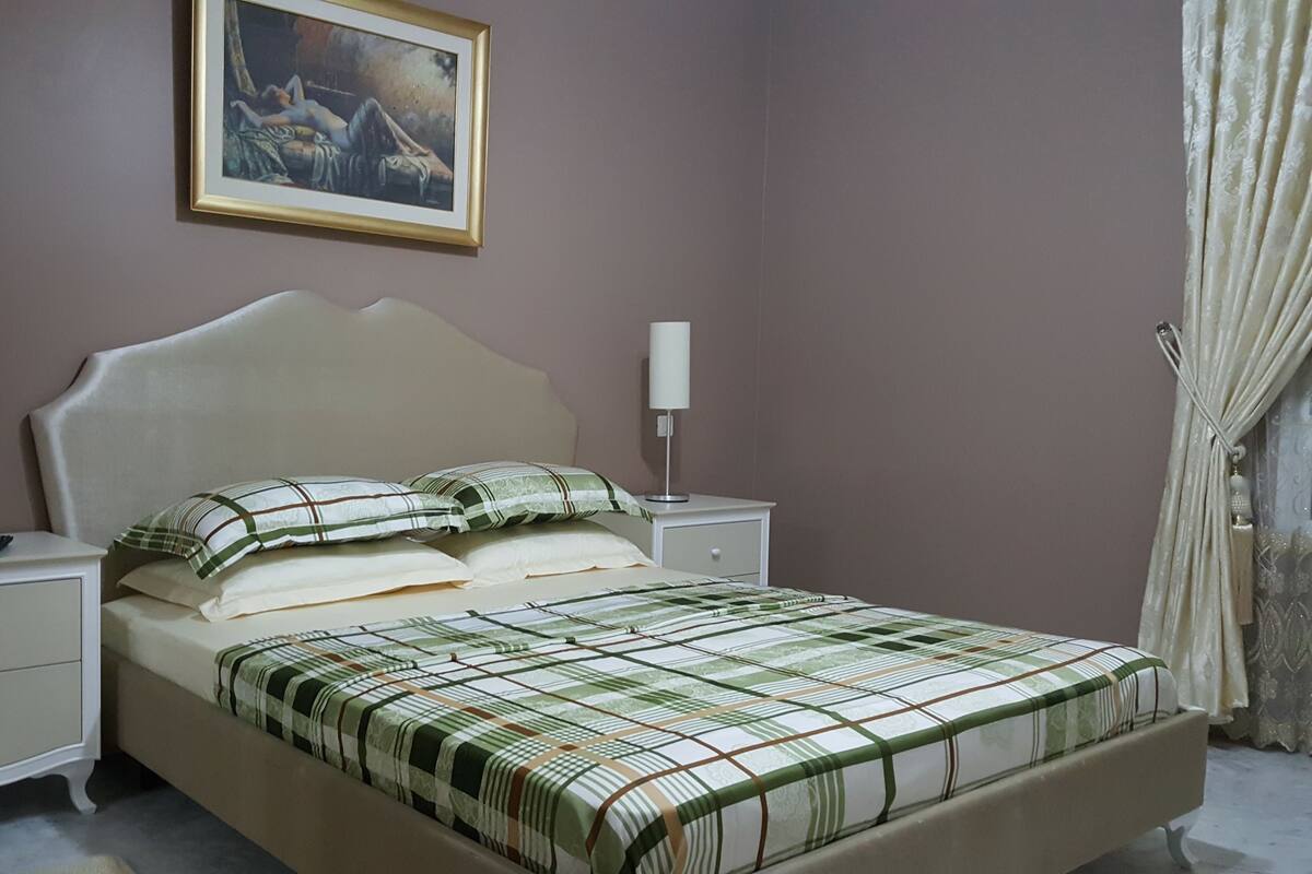 Ein Schlafzimmer mit einem Bett, zwei Nachttischen, einer Lampe und einem Bild an der Wand.