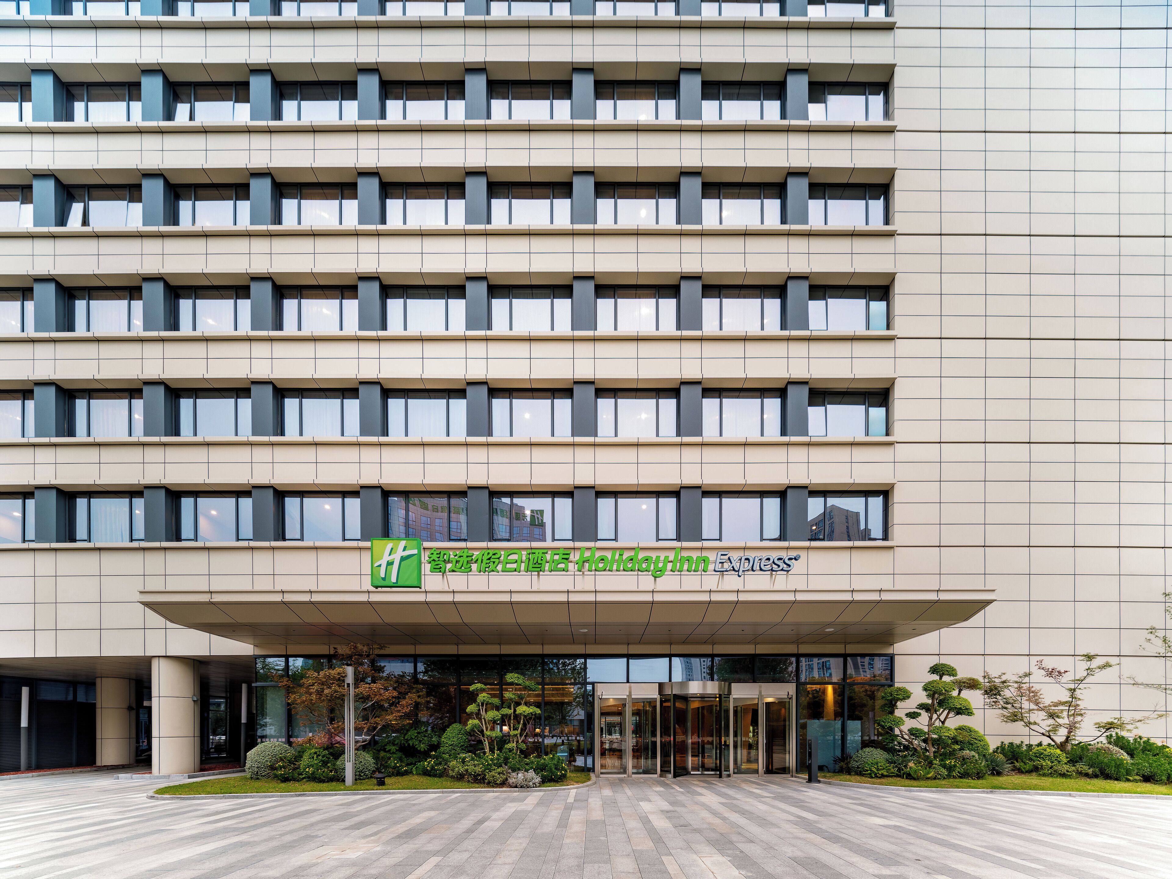 A hotel entrance with a modern facade, large windows, and a covered entrance area.