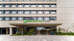 A hotel entrance with a modern facade, large windows, and a covered entrance area. - Holiday Inn Express Wuxi Taihu New City by IHG (Wuxi)