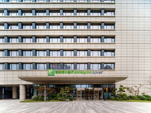 Entrada de hotel com fachada moderna, janelas amplas e área de acesso coberta.