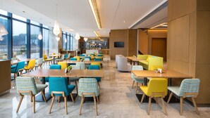 A modern dining area with multiple tables and chairs, large windows, and a television on the wall. - Holiday Inn Express Wuxi Taihu New City by IHG (Wuxi)