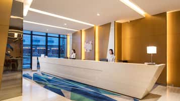 A modern reception desk with two staff members, large windows, and a geometric patterned carpet.