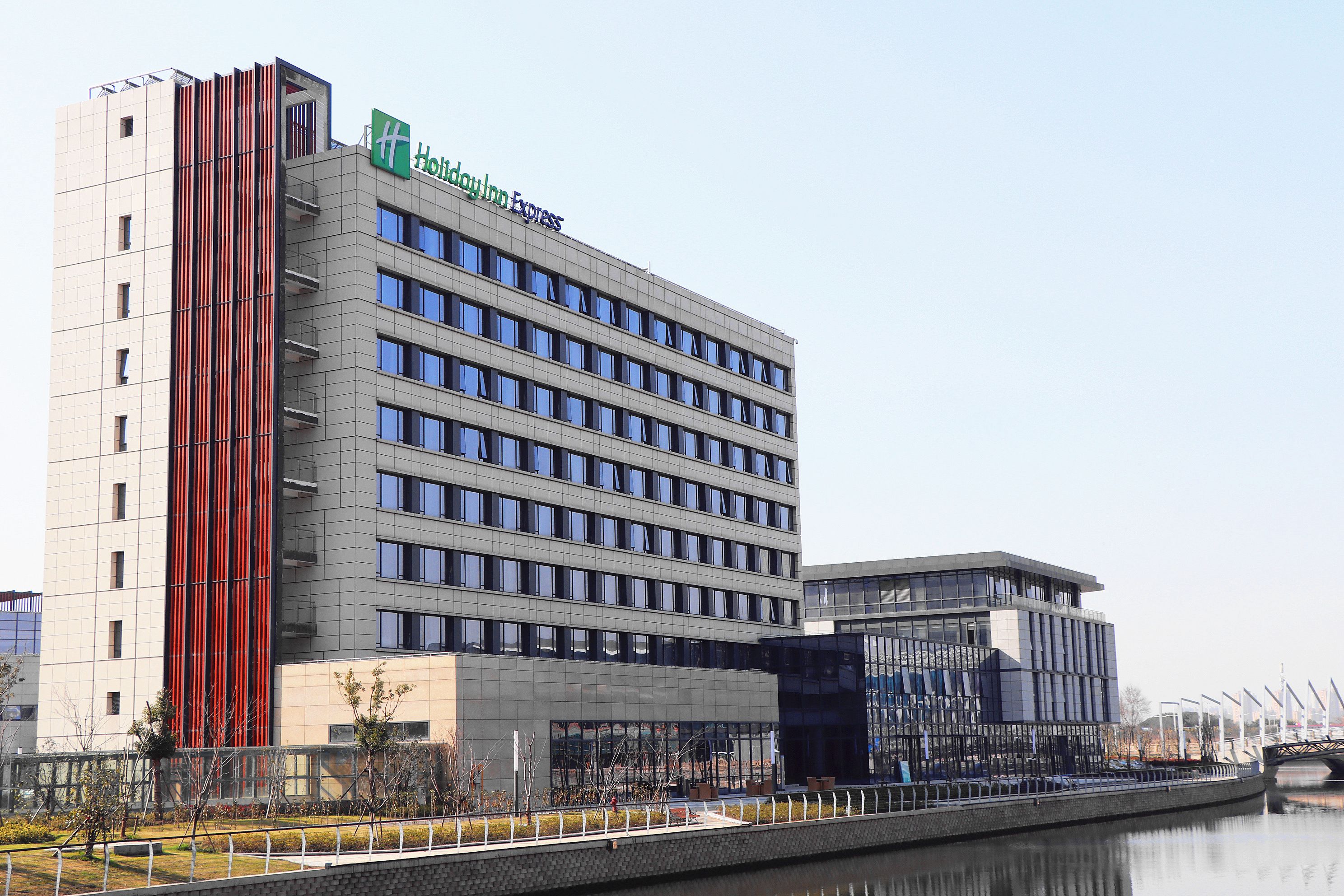 Een modern hotel met een opvallend verticaal rood accent, meerdere verdiepingen en een glazen gevel.
