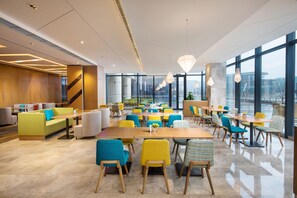 Un espace de restauration moderne, doté de plusieurs tables et chaises, de grandes fenêtres et offrant une vue sur le paysage urbain.