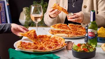 A dining table with pizza, a bottle of Stella Artois beer, and a salad.
