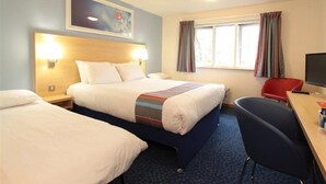 Una camera d'albergo con un letto grande, una scrivania con una sedia, una televisione e una finestra con tende.