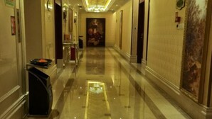 A hotel corridor with a polished floor, a reception desk, and a large painting on the wall. - Vienna Hotel (Shenzhen Longzhu) (Shenzhen)