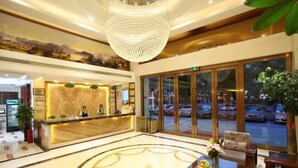 Un hall d’hôtel comprenant un comptoir d’accueil, un espace salon et de grandes fenêtres donnant sur la rue.