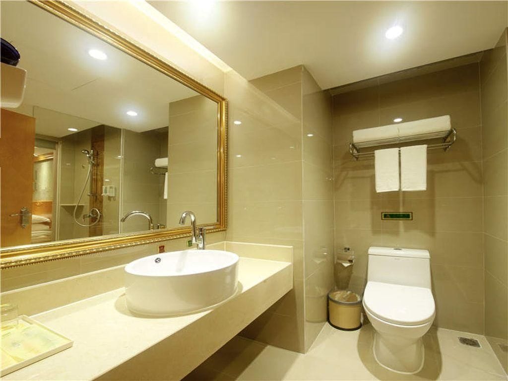A modern bathroom with a large mirror, a sink, a toilet, and a shower area.