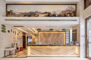 A hotel reception area with a reception desk, a large painting above, and a modern interior design. - Vienna Hotel (Sanya Bay) (Sanya)