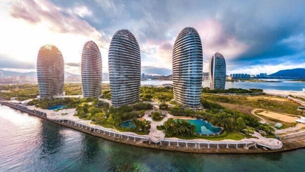 A waterfront property with four modern, cylindrical buildings, a bridge, and a landscaped area with pools. - Vienna Hotel (Sanya Bay) (Sanya)