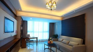 A modern hotel room with a sofa, a TV, a dining table, and a chandelier. - Vienna Hotel (Sanya Bay) (Sanya)