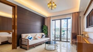 A modern hotel room with a sofa, a small round table, a balcony with a view, and a TV on the wall. - Vienna Hotel (Sanya Bay) (Sanya)
