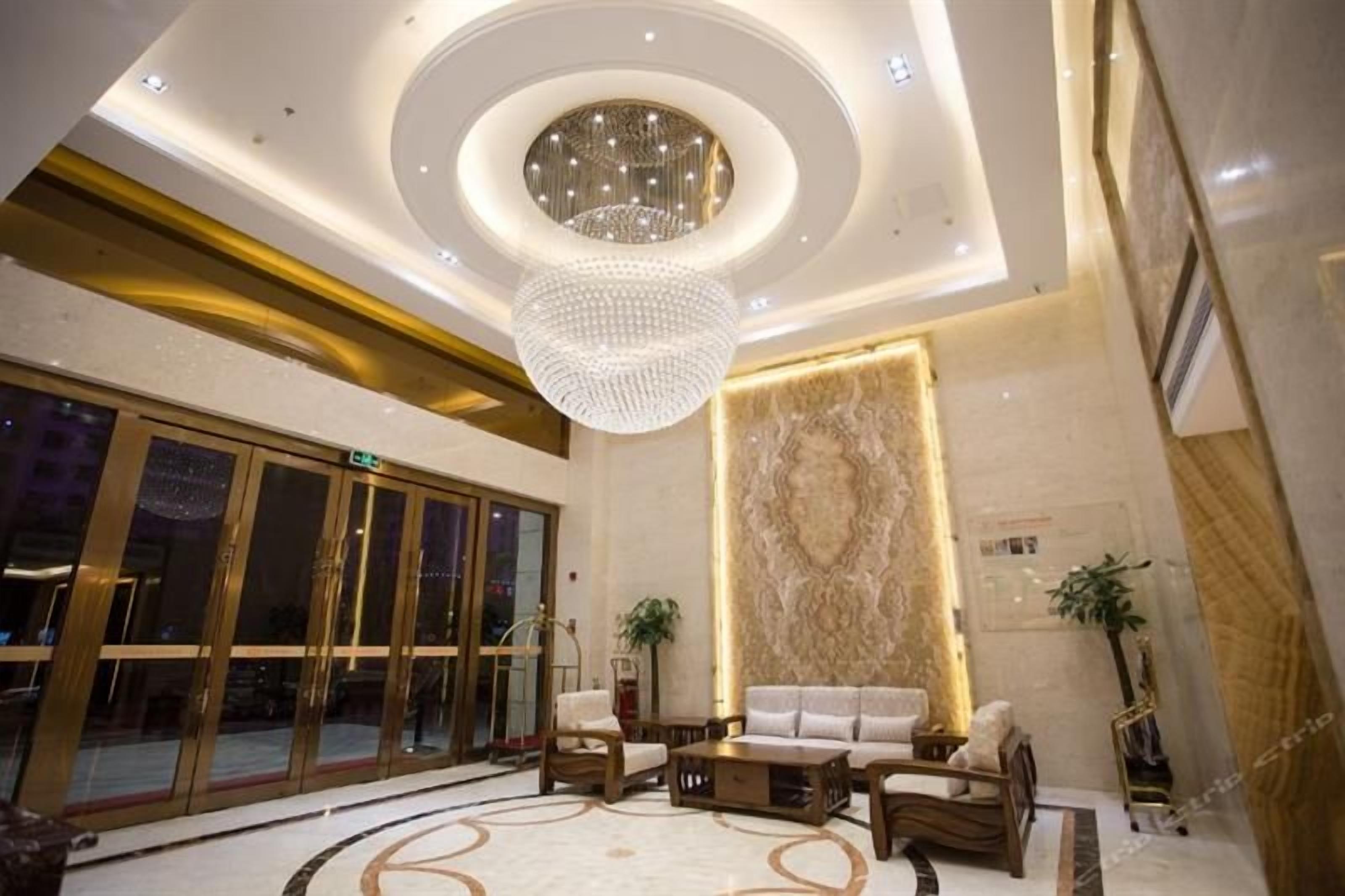 A lobby with a grand chandelier, a reception desk, and a seating area with sofas and a coffee table.