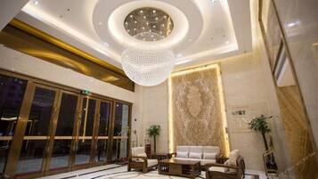 A lobby with a grand chandelier, a reception desk, and a seating area with sofas and a coffee table.
