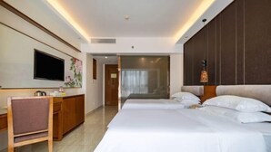A hotel room with a bed, a desk, a chair, a television, and a door leading to another room. - Vienna Hotel (Sanya Bay) (Sanya)