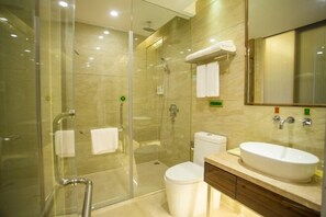 A modern bathroom with a glass-enclosed shower, a white toilet, and a large sink with a mirror above it. - Vienna Hotel (Sanya Bay) (Sanya)