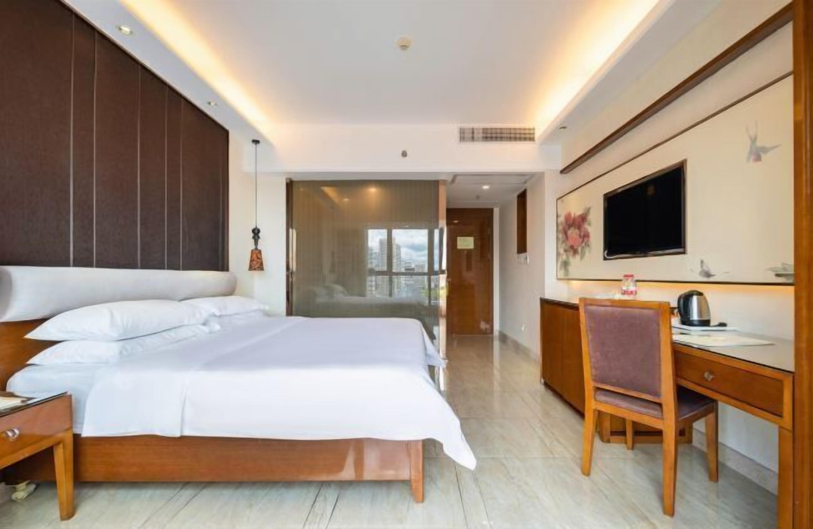 A modern hotel room with a large bed, a desk, and a TV.
