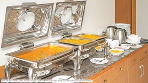 Una mesa de buffet con varias estaciones de servicio, que incluyen una variedad de platos y cubiertos.