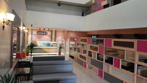Un vestíbulo moderno con mostrador de recepción, zona de estar y estantería de varios niveles con compartimentos para almacenamiento.