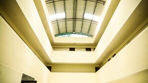 Un atrio de varios niveles con techo de cristal y tragaluces, que cuenta con una escalera central y varios pisos.