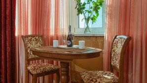 A dining table with two chairs, a vase with flowers, and a bottle on the table. - naDobu Hotel Poznyaki (Kyiv)