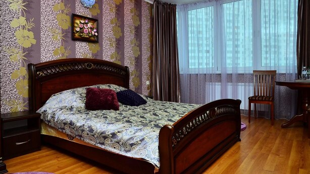 A bedroom with a wooden bed, a nightstand, a chair, and a desk. - naDobu Hotel Poznyaki (Kyiv)