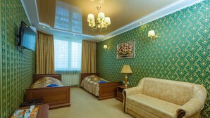 A hotel room with two beds, a sofa, a TV, and a chandelier. - naDobu Hotel Poznyaki (Kyiv)