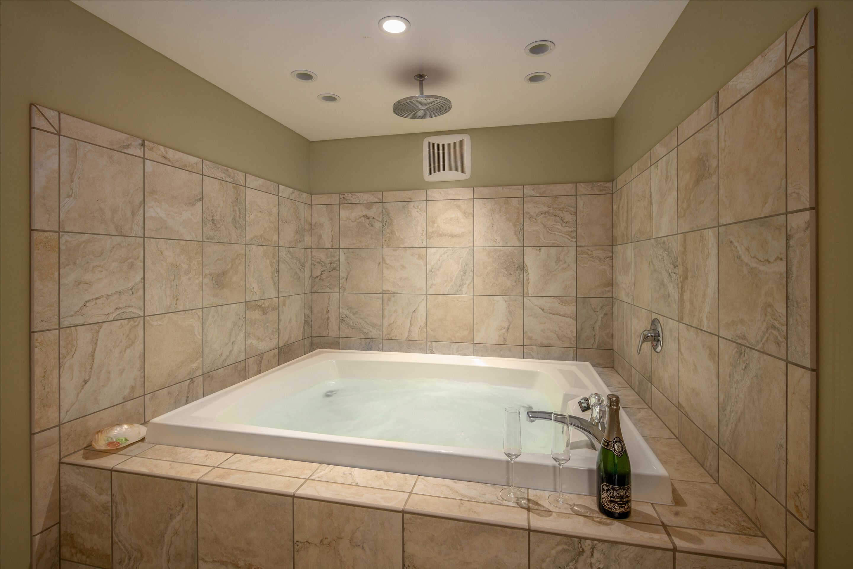 Une salle de bain avec une grande baignoire, une douche et une bouteille de champagne posée à côté.