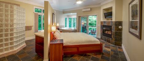 A bedroom with a large bed, a fireplace, and a view of the outdoors.