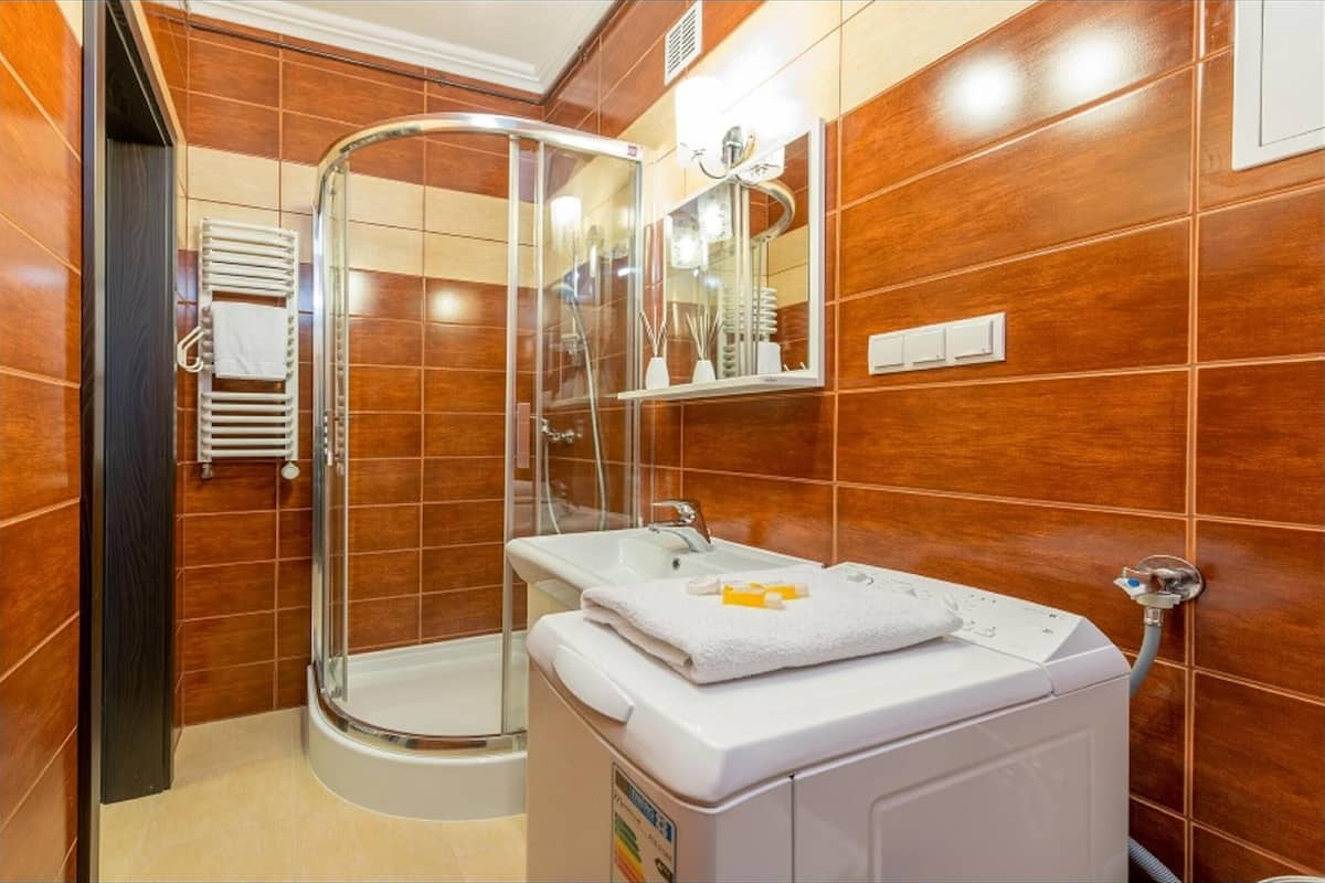 Une salle de bain avec une douche à parois de verre, un lavabo blanc et un porte-serviettes.