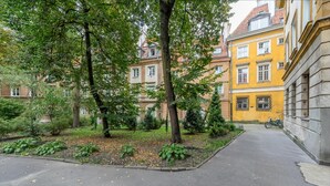 En innergård med träd, en cykel och gula byggnader.