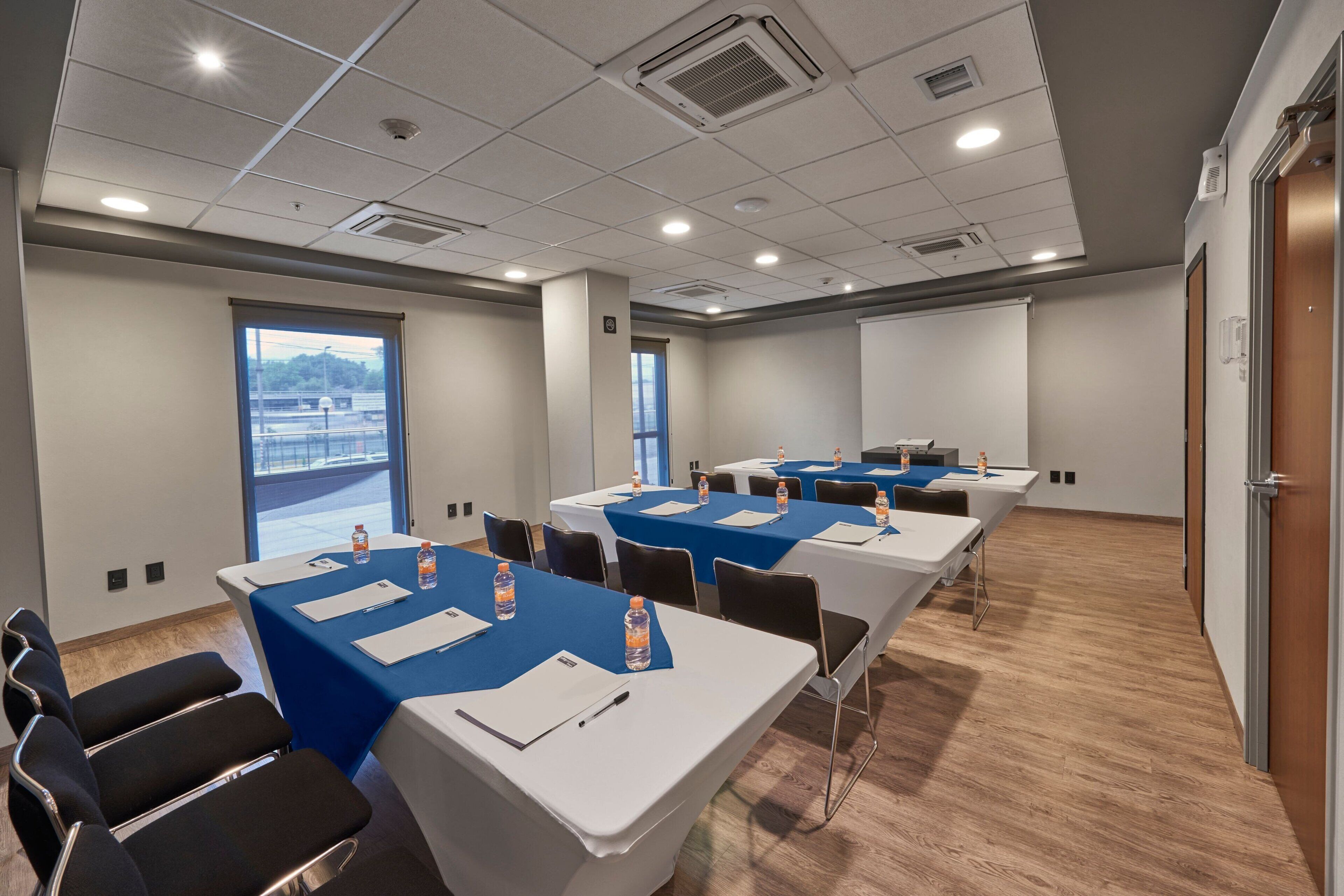 A conference room with tables set for meetings, equipped with water bottles and notepads.