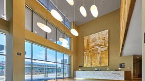 Een ruime lobby met een receptiebalie, grote ramen en een modern plafondontwerp.