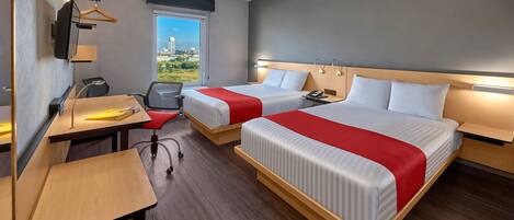 A hotel room with two beds, a desk, a chair, a TV, and a window with a city view.