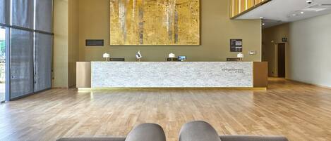 A reception area with a marble counter, two lamps, and a large abstract painting on the wall.