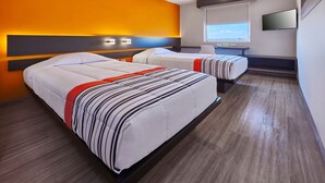 Een hotelkamer met twee bedden, een televisie en een raam met uitzicht op de stad.