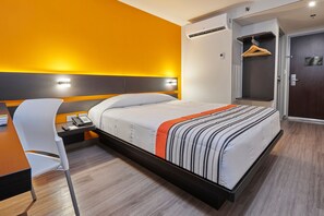Una habitación de hotel moderna con cama, mesita de noche, silla y armario.