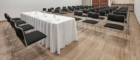 A conference room with a long table, multiple chairs, and a kitchenette area.