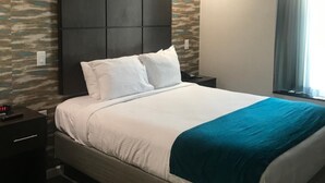 Ein modernes Hotelzimmer mit einem großen Bett, einem dunklen Kopfteil und einer Wand mit Steinmuster.