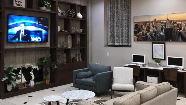 Ein modernes Wohnzimmer mit einem großen Flachbildfernseher, bequemen Sitzgelegenheiten und einem Stadtbild-Wandgemälde.