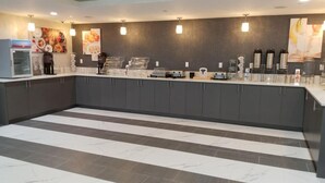 Eine moderne Küchenzeile mit grauen Schränken, einem marmorboden und verschiedenen Geräten, darunter eine Kaffeemaschine und ein Toaster.
