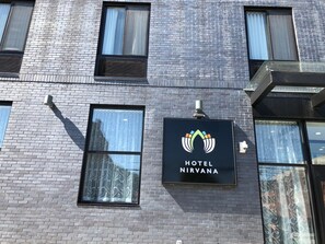 A hotel sign with a logo and the name "HOTEL NIRVANA" on a brick building facade. - Hotel Nirvana (Long Island City)
