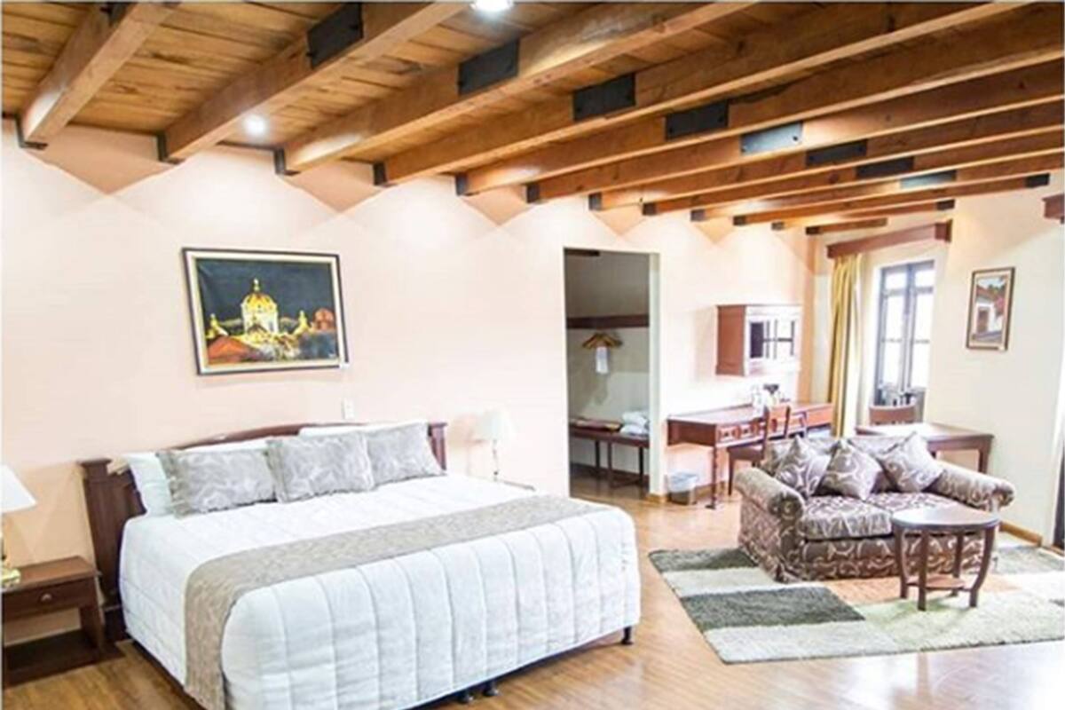 A bedroom with a large bed, a desk, and a sofa.